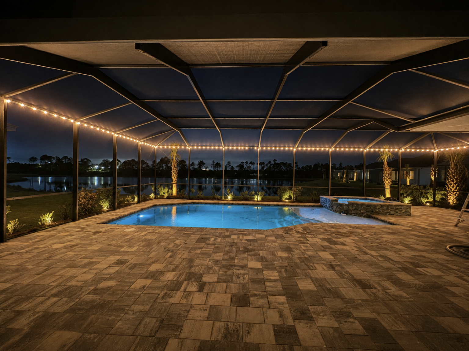 Pool lanai illuminated at night with permanent lights